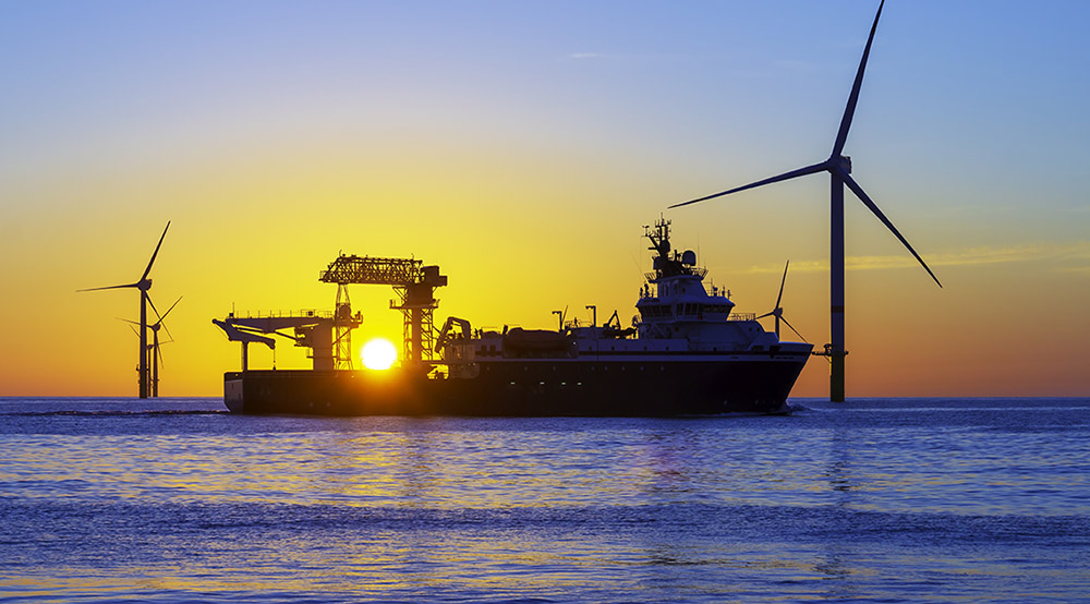 Offshore wind farm and vessel at sunset