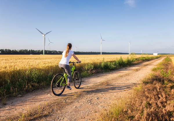 Woman riding a bike next to a wind farm